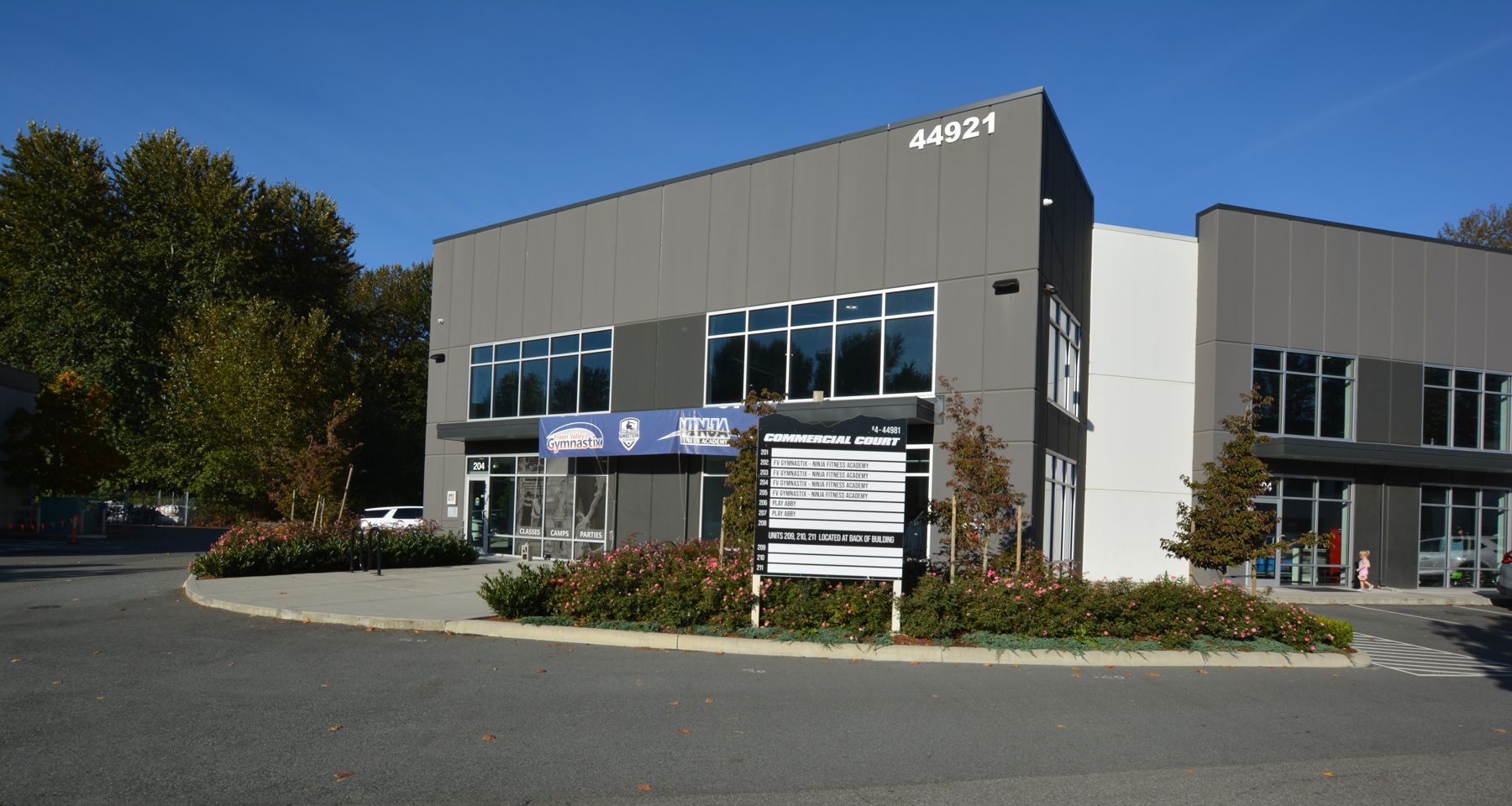 Front of 44921 Commercial Court with tenant banners for a gymnastics club and a ninja fitness academy and the directory sign